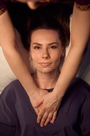 Foto de Vista superior de una mujer joven y serena tumbada en posición supina mientras masajea la palma presionando su región del esternón - Imagen libre de derechos