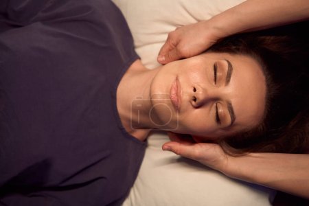 Téléchargez les photos : Vue de dessus de la cliente couchée couchée couchée en masseuse stimulant les acupoints à la base de son crâne - en image libre de droit
