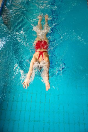Photo for Top view of sportswoman in swimsuit swimming butterfly stroke in sports pool - Royalty Free Image