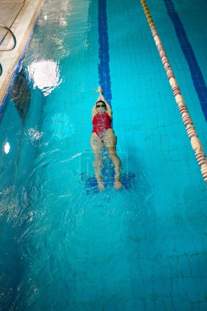 Téléchargez les photos : Vue du dessus de l'athlète féminine en lunettes et bonnet de bain nageant sur le dos sous l'eau - en image libre de droit