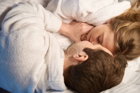 Téléchargez les photos : Top-view homme et femme couchés dans le lit face à face, couple dans l'amour câlins et câlins, profiter de l'autre, flirt et affection, romance - en image libre de droit