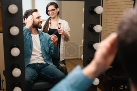 Photo for Client in a barbershop communicates with a woman barber, the master has working tools in his hands - Royalty Free Image