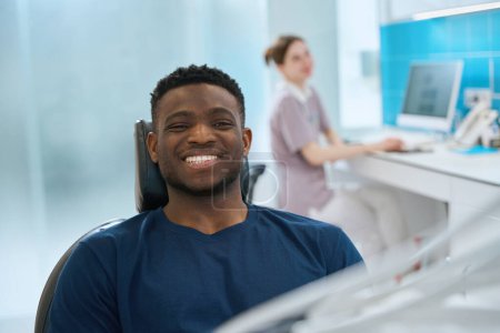 Téléchargez les photos : Homme stomatologue client regardant la caméra avec un sourire sain et blanc assis à la chaise dentaire confortable, visite clinique stomatologique privée - en image libre de droit