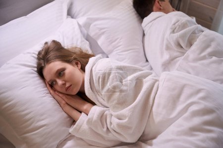 Foto de Mujer con albornoz y almohada en sábanas blancas - Imagen libre de derechos