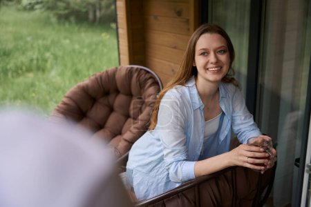 Foto de Mujer feliz sentado en silla en casa de campo terraza abd celebración de la taza de té - Imagen libre de derechos