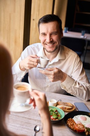 Foto de Hombre de negocios llamando a la mujer en la cita a la cafetería, pareja desayunando y bebiendo café recién hecho, comunicándose entre sí, retrospectiva - Imagen libre de derechos