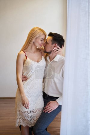 Foto de Hermosa mujer en vestido blanco sensual abrazando a su hombre guapo, pareja mirando el uno al otro con deseo y seducción, amor - Imagen libre de derechos