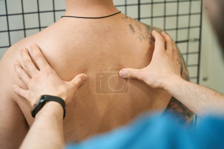Photo for Cropped photo of physical therapist palpating male patient paravertebral muscles in upper back region - Royalty Free Image