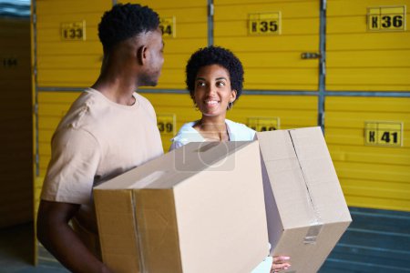 Foto de Chicos afroamericanos en un almacén con cajas de cartón en sus manos, celdas amarillas están numeradas - Imagen libre de derechos
