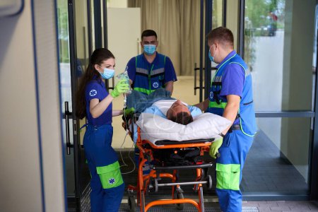 Foto de Médicos de ambulancia llevaron al hombre a la sala de emergencias, el paciente recibe un gotero con analgésicos - Imagen libre de derechos