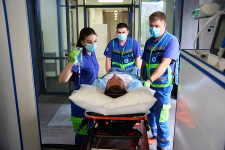 Foto de Equipo de paramédicos llevó al hombre a la sala de emergencias, el paciente recibe un gotero con analgésicos - Imagen libre de derechos