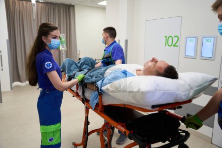 Foto de Equipo médico trajo al hombre a la sala de emergencias, el paciente fue puesto en un goteo con analgésicos - Imagen libre de derechos