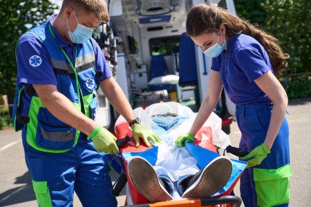 Foto de Los paramédicos pusieron al paciente para el transporte en un colchón de vacío, los médicos usando una camilla especial - Imagen libre de derechos