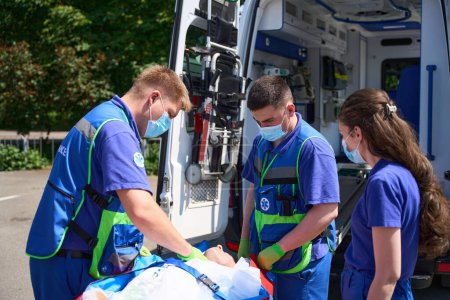 Téléchargez les photos : Un ambulancier répare le patient pour le transporter sur un matelas aspirateur, la victime est chargée dans une ambulance - en image libre de droit