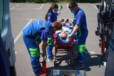 Téléchargez les photos : Les médecins utilisent un matelas à vide pour transporter un patient souffrant de polytraumatisme, un ambulancier gonfle le matelas avec une pompe - en image libre de droit