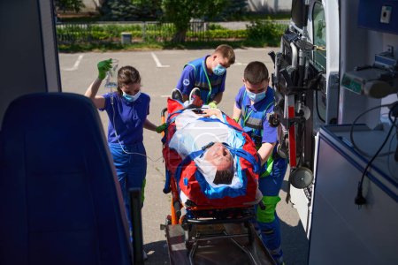 Téléchargez les photos : L'équipe ambulancière transporte un patient avec un polytraumatisme, les médecins utilisent un matelas à vide spécial - en image libre de droit