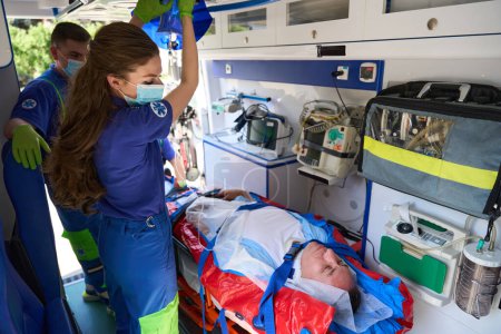 Téléchargez les photos : L'équipe d'ambulanciers transporte un patient avec un polytraumatisme, un matelas à vide spécial est utilisé pour réparer le patient - en image libre de droit