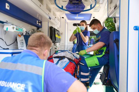 Les ambulanciers mettent le patient sur un compte-gouttes et remplissent un questionnaire, une équipe de médecins transporte un patient avec polytraumatisme