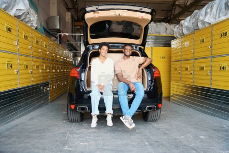 Photo for African American guys are sitting in the open trunk of a car, they are in storage - Royalty Free Image