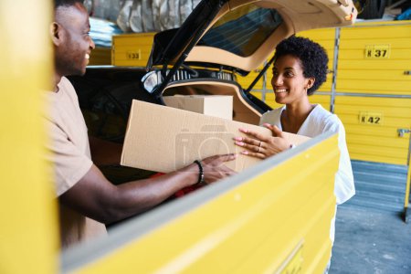 Photo for African American guys unload boxes of things from the car, they are in the storage service - Royalty Free Image