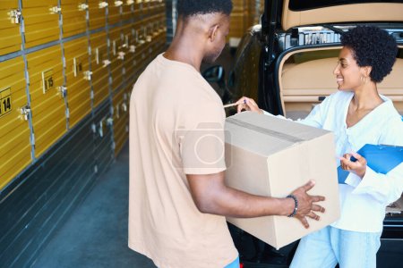 Photo for Woman manager makes an inventory of things being deposited, next to a man with a cardboard box - Royalty Free Image