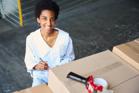 Photo for Beautiful woman makes an inventory of things being deposited, in front of her there are many cardboard boxes - Royalty Free Image
