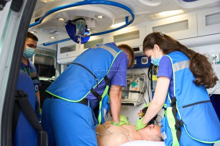 Téléchargez les photos : Réanimation cardiopulmonaire efficace d'un patient dans une ambulance, paramédicaux faisant un massage cardiaque - en image libre de droit