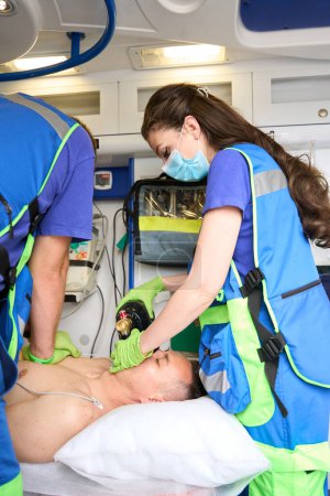 Téléchargez les photos : Réanimation cardiopulmonaire d'un patient dans une ambulance, ambulanciers faisant un massage cardiaque - en image libre de droit