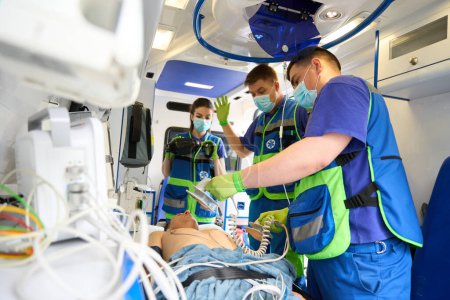 Téléchargez les photos : Équipage ambulancier réanime un patient dans une ambulance en utilisant un équipement moderne - en image libre de droit