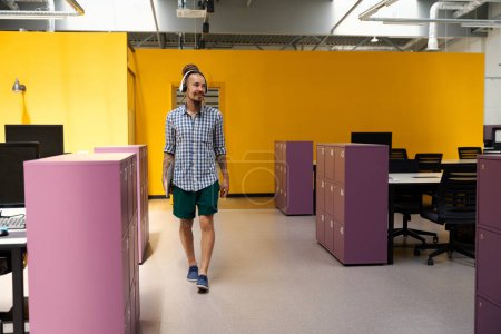 Foto de Especialista en informática con barba y bigote entra en una habitación con taquillas rosas, paredes amarillas en la habitación - Imagen libre de derechos