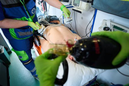 Téléchargez les photos : Une équipe mobile ressuscite un blessé dans une ambulance à l'aide d'un défibrillateur et d'un sac respiratoire - en image libre de droit