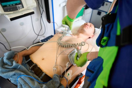 Téléchargez les photos : Les ambulanciers utilisent un défibrillateur pour réanimer le patient, le médecin applique des électrodes sur le torse des patients - en image libre de droit