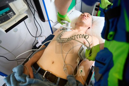 Téléchargez les photos : Equipage ambulancier utilise un défibrillateur pour ressusciter un patient, le médecin a appliqué des électrodes sur le torse des patients - en image libre de droit