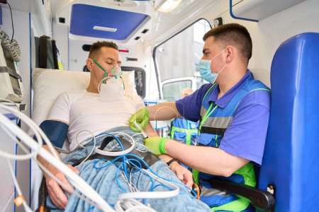 Téléchargez les photos : Médecin injectant des médicaments au patient en ambulance, victime portant un masque à oxygène - en image libre de droit