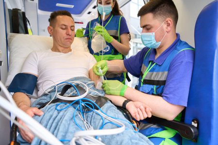 Foto de Médico del equipo móvil que administra una inyección a un paciente en una ambulancia - Imagen libre de derechos