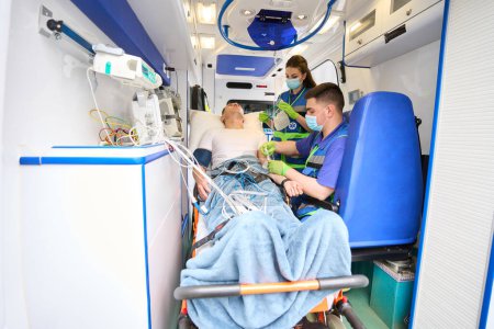 Foto de Equipo móvil de paramédicos conecta al paciente con el goteo en la ambulancia - Imagen libre de derechos