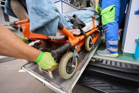 Photo for Loading a stretcher with a patient into an ambulance, paramedics work in protective gloves - Royalty Free Image
