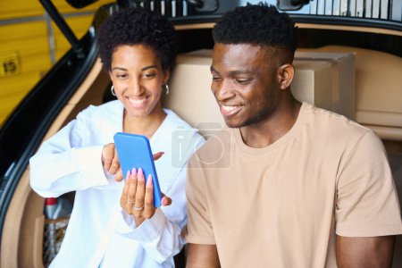 Photo for African American woman shows something on her phone to her boyfriend, they arrived at the storage service - Royalty Free Image