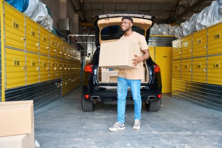 Photo for Service client transfers a cardboard box with things to a cell, he brought things for storage - Royalty Free Image