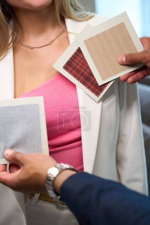 Téléchargez les photos : Photo recadrée de mains de créateurs de mode tenant des échantillons à côté des vêtements du client - en image libre de droit
