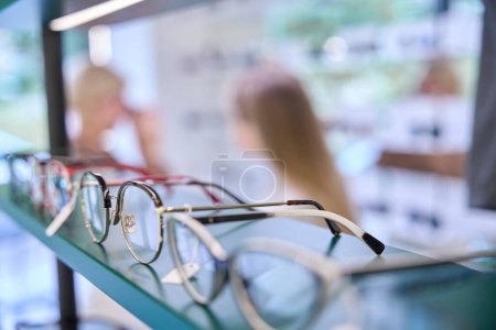 Foto de Consultor selecciona marcos para un cliente, hay una amplia selección de gafas en exhibición - Imagen libre de derechos