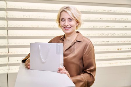 Téléchargez les photos : Client souriant d'un salon d'optique avec un achat en forfait, un large choix de montures dans le salon - en image libre de droit
