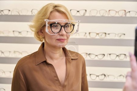 Photo for Consultant takes a photo of a woman wearing a trial frame, the salon has a wide selection of frames - Royalty Free Image