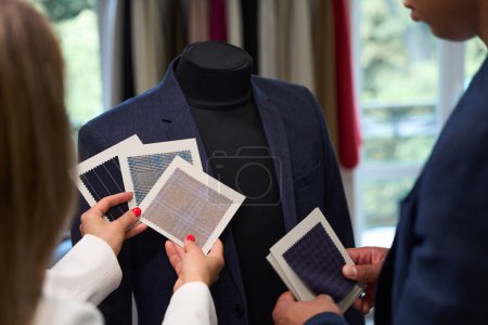Téléchargez les photos : Photo recadrée de couturiers tenant des échantillons devant la veste de costume sur le mannequin - en image libre de droit