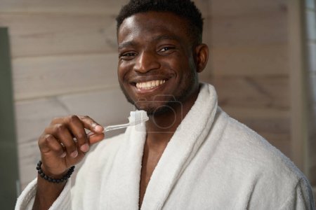 Foto de El tipo con una sonrisa de dientes blancos está listo para cepillarse los dientes, usa un cepillo de dientes y pasta de dientes - Imagen libre de derechos