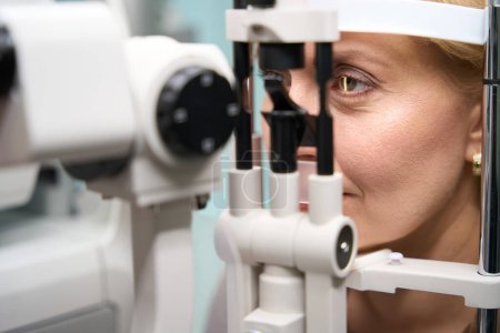 Foto de La cabeza de la mujer se fija frente a un dispositivo oftalmológico especial, una dama en una cita con un oftalmólogo - Imagen libre de derechos