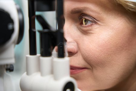 Foto de La cabeza del cliente se fija frente a un dispositivo oftálmico especial, una dama en una cita con un oftalmólogo - Imagen libre de derechos