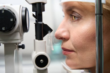 Foto de Cliente de mediana edad sometido a un examen oftalmológico, un dispositivo moderno se utiliza durante una cita con un oftalmólogo - Imagen libre de derechos