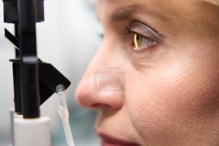 Foto de Señora de mediana edad sometida a un examen oftalmológico, en una cita con un oftalmólogo, se utiliza un dispositivo moderno - Imagen libre de derechos