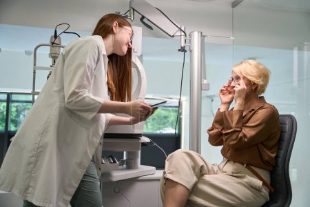 Foto de Oftalmólogo en el lugar de trabajo se comunica con un paciente, el médico utiliza aparatos profesionales - Imagen libre de derechos